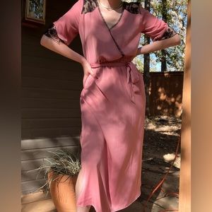 Pink satin faux wrap slip dress with black lace detail, tie waist, leg slits